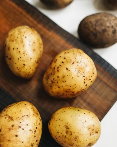 Close-up of fresh potatoes on a wooden board, highlighting their natural texture.